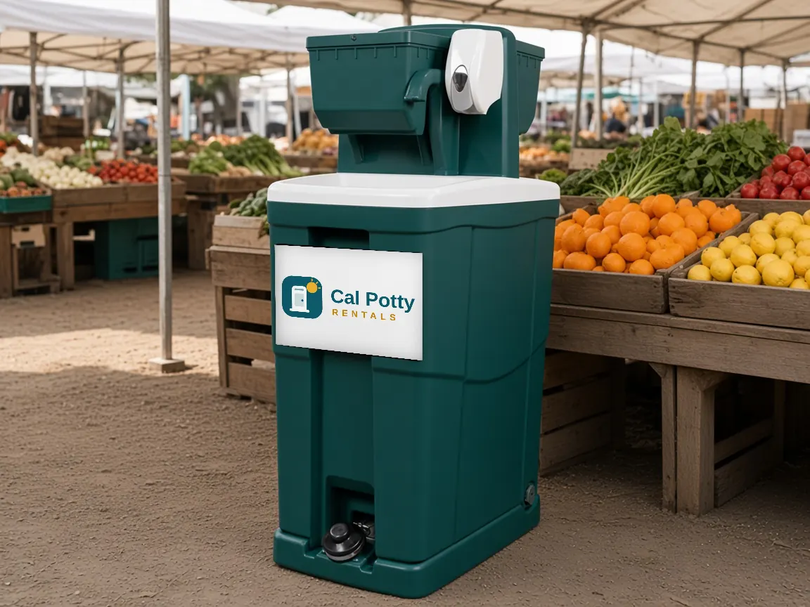 A teal handwashing station at a farmers market in front of produce stalls